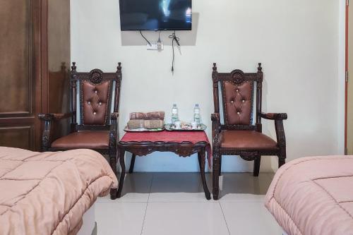 a bedroom with two chairs and a table and a tv at RedDoorz Syariah @ Penginapan Citra Alam 2 in Sungaitutung