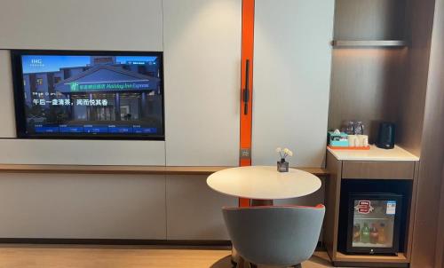 a room with a table and a tv on a wall at Holiday Inn Express Shanghai Pujiang Lianhang Road by IHG in Shanghai