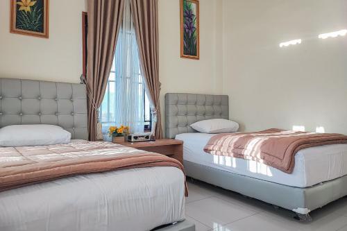 a bedroom with two beds and a window at RedDoorz Syariah @ Penginapan Citra Alam 2 in Sungaitutung