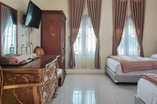 a bedroom with a dresser and a bed and a desk at RedDoorz Syariah @ Penginapan Citra Alam 2 in Sungaitutung