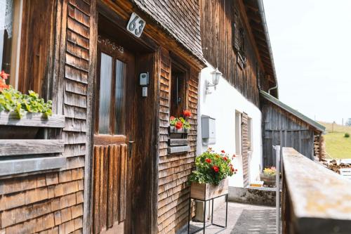 ein Holzgebäude mit einer Tür und Blumen darauf in der Unterkunft Haus Berchtold am Hüttersberg in Doren