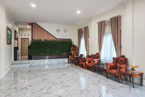 a lobby with leather chairs and a marble floor at RedDoorz Syariah @ Penginapan Citra Alam 2 in Sungaitutung