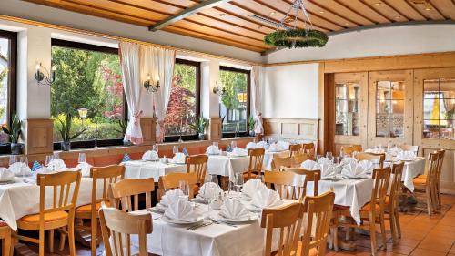Styles Hotel Unterföhring في ميونخ: مطعم بطاولات بيضاء وكراسي ونوافذ
