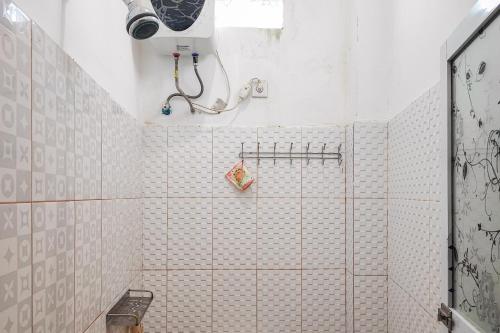 a bathroom with a shower with white tiled walls at RedDoorz Syariah @ Penginapan Citra Alam 2 in Sungaitutung