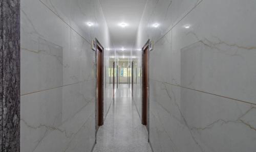 a hallway with white marble walls and a long corridor at Treebo Pranav Park in Vellore