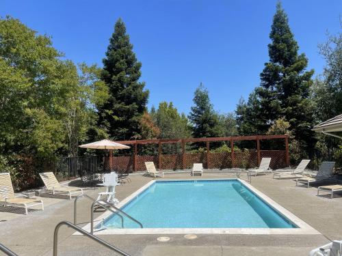 a swimming pool with chairs and an umbrella at Rocklin Park Hotel in Rocklin