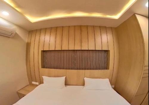 a bed in a small room with a wooden wall at Hotel Prago by Green Deer Varanasi in Varanasi