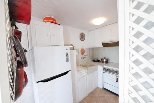 a kitchen with white cabinets and a white refrigerator at Traditional House under the Clock Tower with Sweet View in Poros