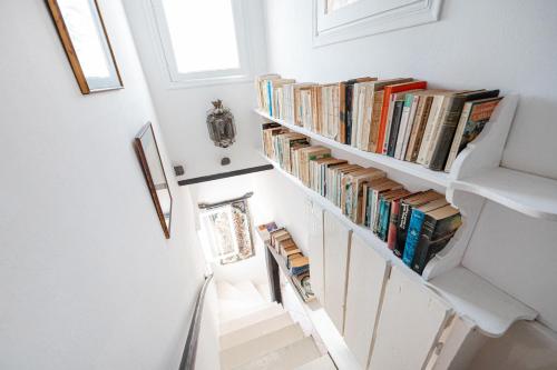 a staircase with white shelves filled with books at Traditional House under the Clock Tower with Sweet View in Poros