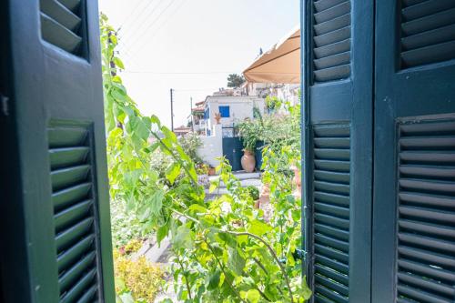 an open window view of a garden with plants at Traditional House under the Clock Tower with Sweet View in Poros