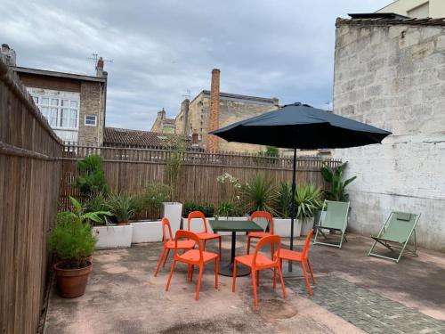 une terrasse avec une table, des chaises et un parasol dans l'établissement Le Beaufleury et sa terrasse à la Victoire, à Bordeaux