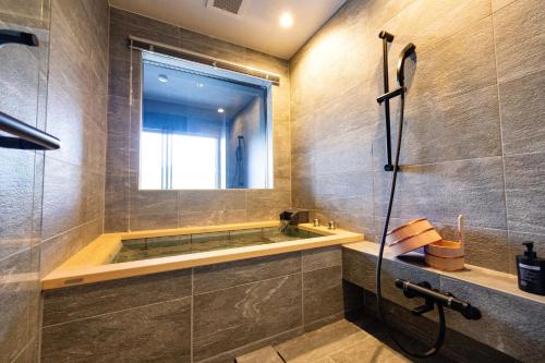 a bathroom with a tub and a shower with a window at Urari Takeo Garden Terrace Spa Resorts in Takeo