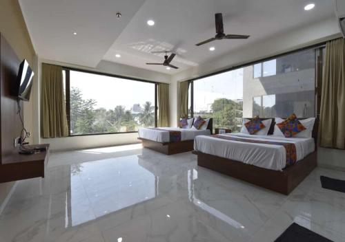 a bedroom with two beds and a large window at Hotel Infini Palace City Center in Surat