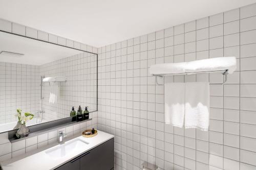 a white tiled bathroom with a sink and a mirror at base-Beijing Wangfujing Serviced Apartment- in Hutong &Bike rental &Close to Forbidden City, Tian'anmen Square &Subway nearby &Free coffee &Washing machine,Kitchen &Restaurant discount &English speaking &High speed free WiFi in Beijing