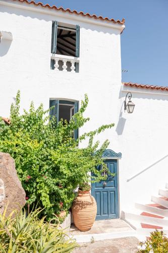 a white house with a blue door and a plant at Traditional House under the Clock Tower with Sweet View in Poros