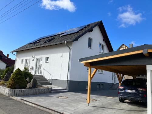 a white house with a solar roof at Ferienwohnung Rhönperle Dermbach in Dermbach