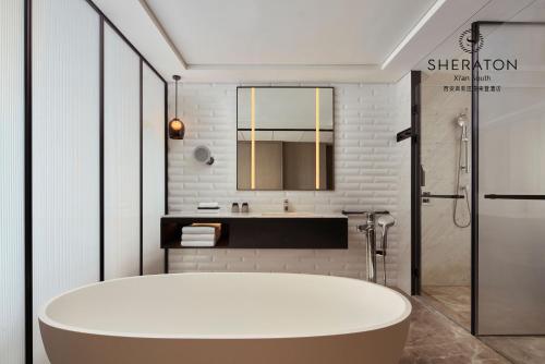 ein Badezimmer mit einer weißen Badewanne und einem Waschbecken in der Unterkunft Sheraton Xi'an South in Xi'an