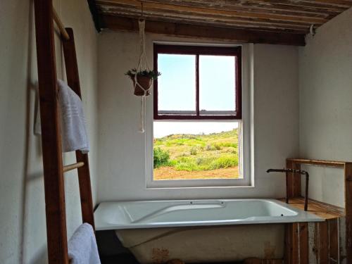 uma banheira na casa de banho com uma janela em Klein Doorn Farm Stay em Oudtshoorn
