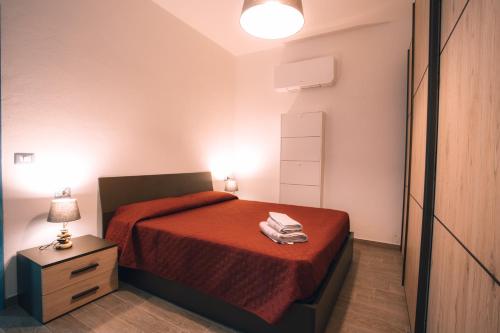 una piccola camera da letto con un letto con copriletto rosso di CASA LUCIA , ricarica auto elettrica GRATUITA a Siniscola