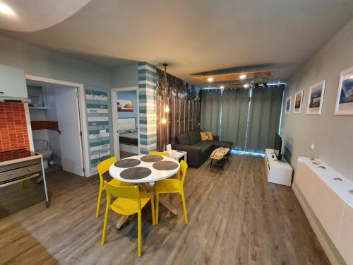 a living room with a table and yellow chairs at Surf Station Tenerife Holiday Apartment Las Americas in Playa de las Americas