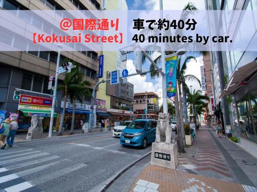 a city street with a blue car driving down the street at HOTEL PACIFIC VIEW Rental car included & pet-friendly in Okinawa City