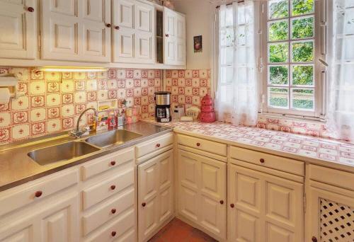 une cuisine avec des armoires blanches, un évier et une fenêtre dans l'établissement Villa Rospico - Plage de sable à 250m, à Névez