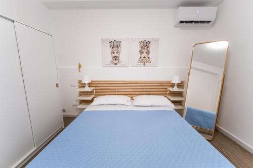 1 dormitorio con cama azul y espejo en Matilde’s Holiday House en Terrasini