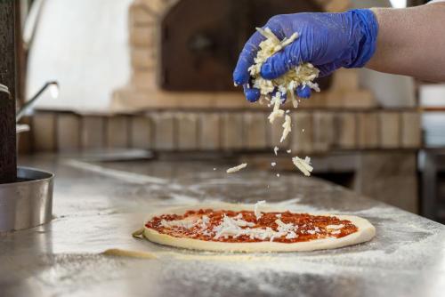 a person is sprinkling sauce on a pizza at Helena Park - Ultra All Inclusive in Sunny Beach
