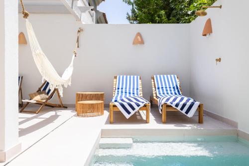 Duas cadeiras e uma rede de descanso num pátio com piscina. em Esencia Marbella Casas Boutique em Estepona