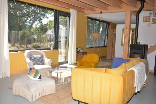 d'un salon avec un canapé et des fauteuils jaunes. dans l'établissement Le charme du bois - 8 à 10 personnes- Maison entière, à La Turballe