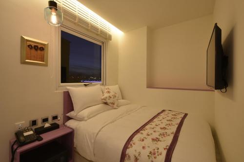 a small bedroom with a bed and a window at DG Hotel in Taipei