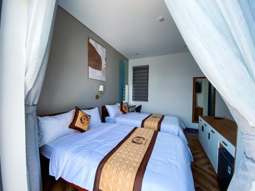 two twin beds in a room with white walls at Khách sạn Miami Ninh Thuận in Phan Rang