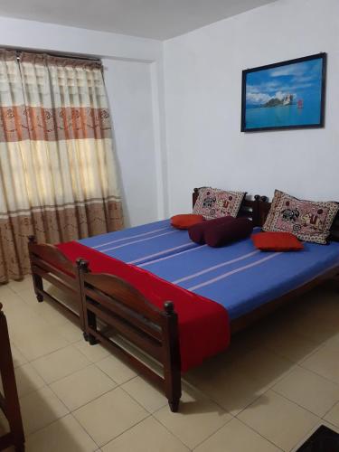 een slaapkamer met een groot bed met blauwe en rode lakens bij Hotel Kintop in Udugama