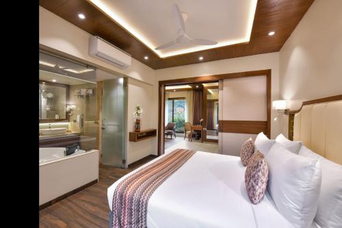 a bedroom with a large white bed and a bathroom at Arova Woods Zinc Journey by The Fern, Lonavala in Lonavala