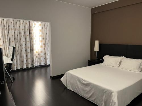 a bedroom with a white bed and a window at Casas de Luanda GH-Alvalade in Luanda