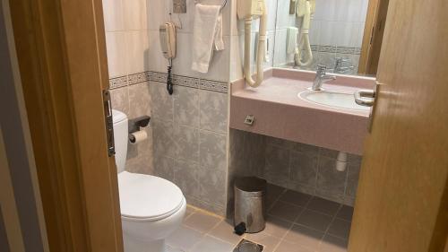een badkamer met een toilet, een wastafel en een telefoon bij SUN & SANDS HOTEL LLC in Dubai