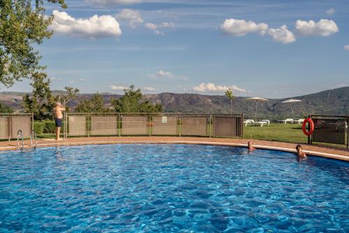 a man standing next to a large swimming pool at Parador de Verín in Monterrei