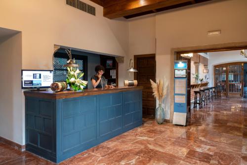 a woman standing at a blue counter in a kitchen at Parador de Verín in Monterrei