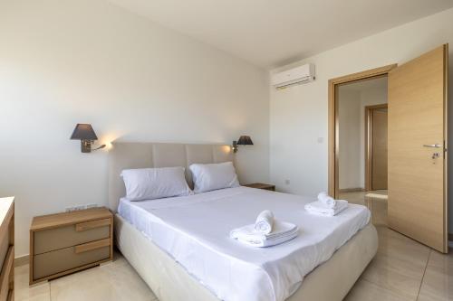 um quarto com uma cama branca e toalhas em New top floor apartment enjoy opening views em San Ġwann