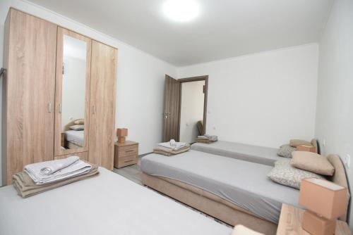 a white bedroom with two beds and a mirror at Apartment Miske in Ivanica