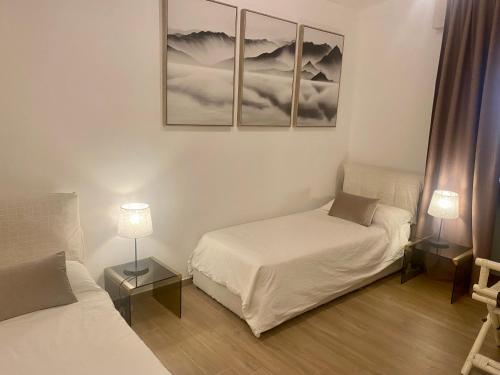 two beds in a room with two lamps and pictures on the wall at Villa Elisa in Punta Ala