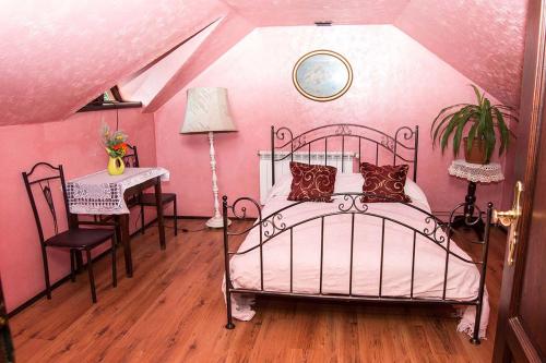 a pink bedroom with a bed and a table at Bocianówka in Baranów Sandomierski