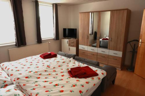 Haus am Kroatenbach في Lautenthal: غرفة نوم عليها سرير ومخدات حمراء