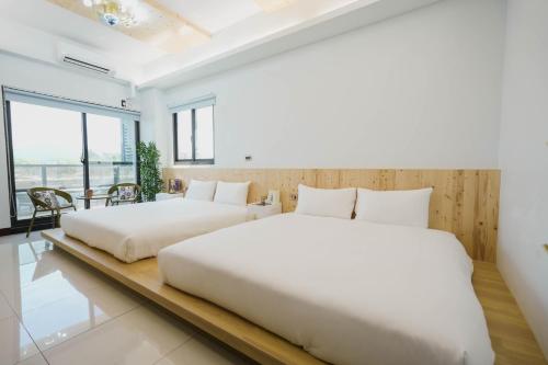 two beds in a bedroom with white walls and windows at 墾丁包棟民宿-曜凱樂 in Jen-shou
