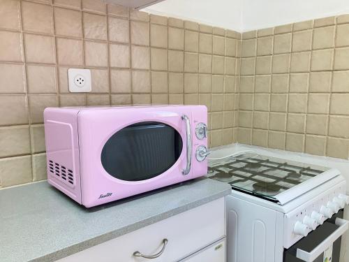 a pink microwave sitting on a counter next to a stove at Serene Oasis @ Arad in Arad