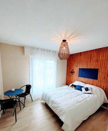 une chambre avec un grand lit blanc et une table dans l'établissement Traezh ar vag - Appartement Plage Perros-Guirec, à Perros-Guirec