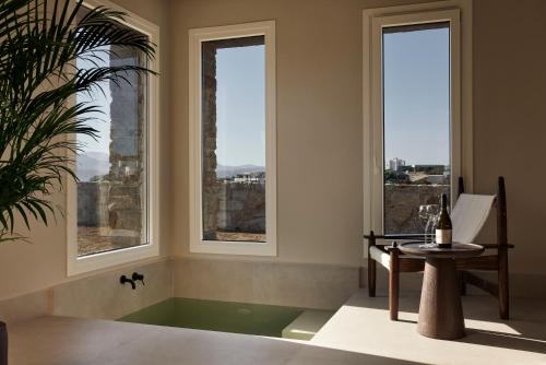 a room with windows and a tub with a table at Naxian Rhapsody in Stelida