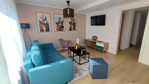 ein Wohnzimmer mit einem blauen Sofa und einem Tisch in der Unterkunft ELApart by Homely Stay - Moderne Apartments mit Self-Check-in in Bad Kissingen