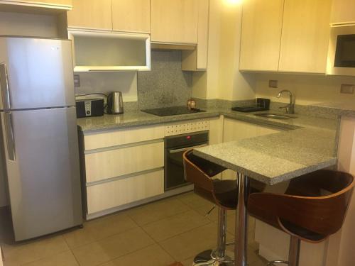 a kitchen with a refrigerator and a counter with stools at DEPARTAMENTOS TERMAS DE CHILLAN in Nevados de Chillan