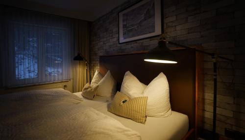 ein Schlafzimmer mit einem Bett mit weißen Kissen und einer Lampe in der Unterkunft Hotel Grüne Tanne Mandelholz in Elend